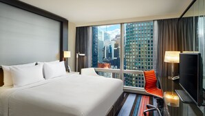 Una habitación de hotel con una cama grande, televisión, escritorio y vistas a la ciudad.