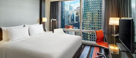 A hotel room with a large bed, a TV, a desk, and a view of the cityscape.