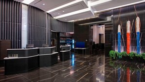 A modern lobby with a reception desk, a digital screen, and a decorative wall with vertical elements. - Courtyard by Marriott New York Manhattan / Central Park (New York)
