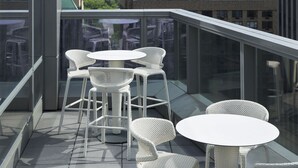 Terraza en la azotea con muebles de mimbre blanco y vistas a la ciudad.