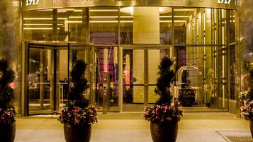 Entrada de un hotel con fachada de vidrio, plantas grandes en macetas y el nombre 'Marriott Courtyard' exhibido arriba.