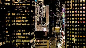 A nighttime cityscape with high-rise buildings, illuminated windows, and a prominent tower.