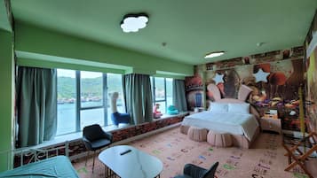 A room with a bed, a chair, a small table, and a window with curtains.