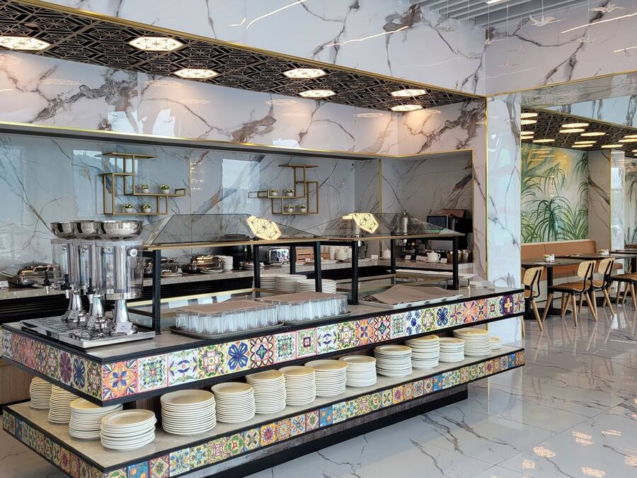 A buffet area with marble walls, a variety of dishes, and a modern ceiling design.