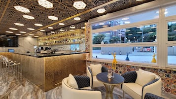 A bar area with a marble countertop, seating with cushions, and a patterned wall.