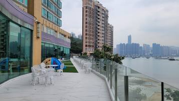 Terraza frente al agua con mesas al aire libre y vistas del horizonte urbano.