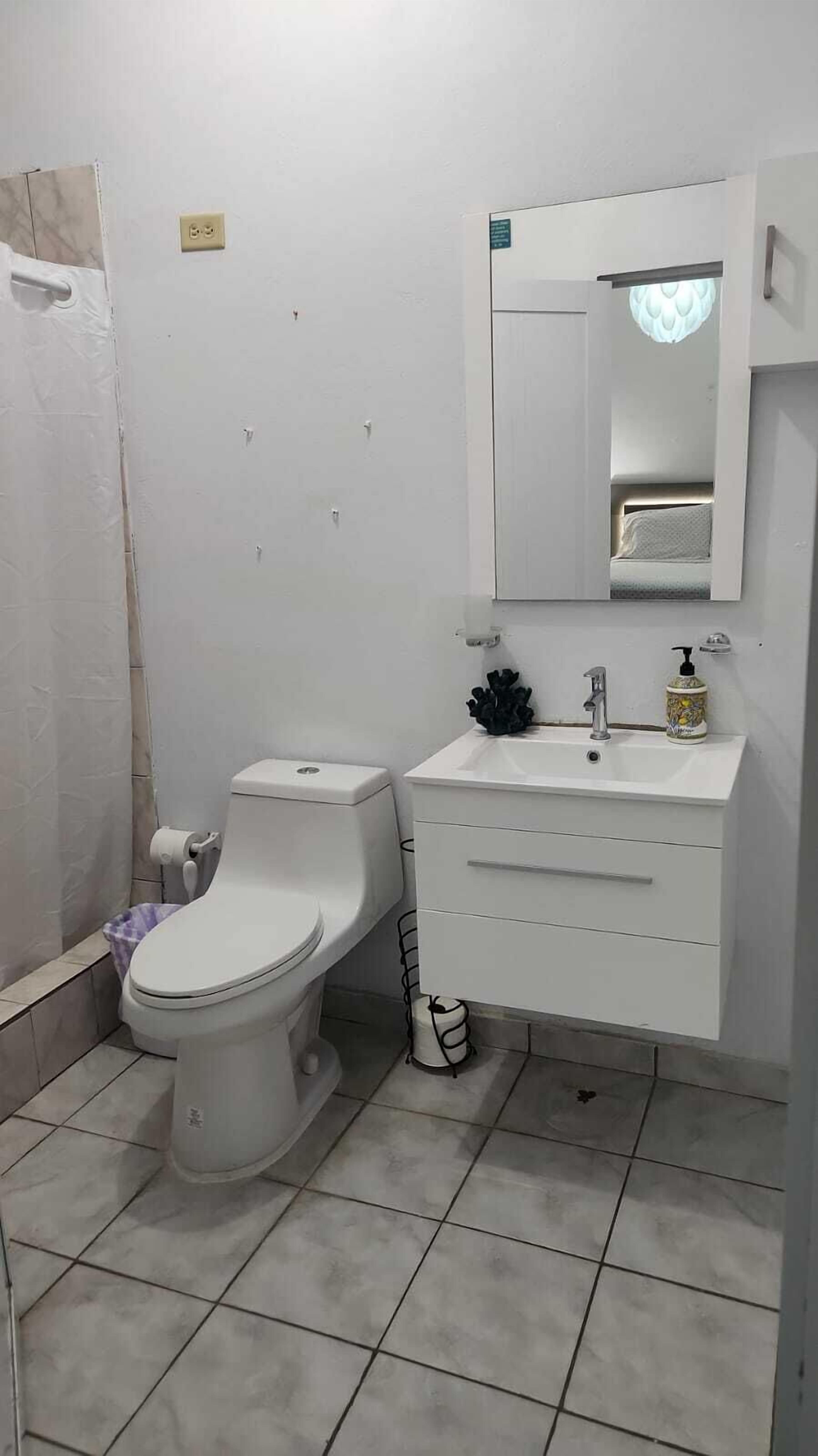 Une salle de bain avec des toilettes, un lavabo et un miroir.