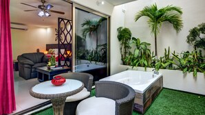 Ein modernes Badezimmer mit einer großen Badewanne, einem Deckenventilator und diversen Pflanzen.