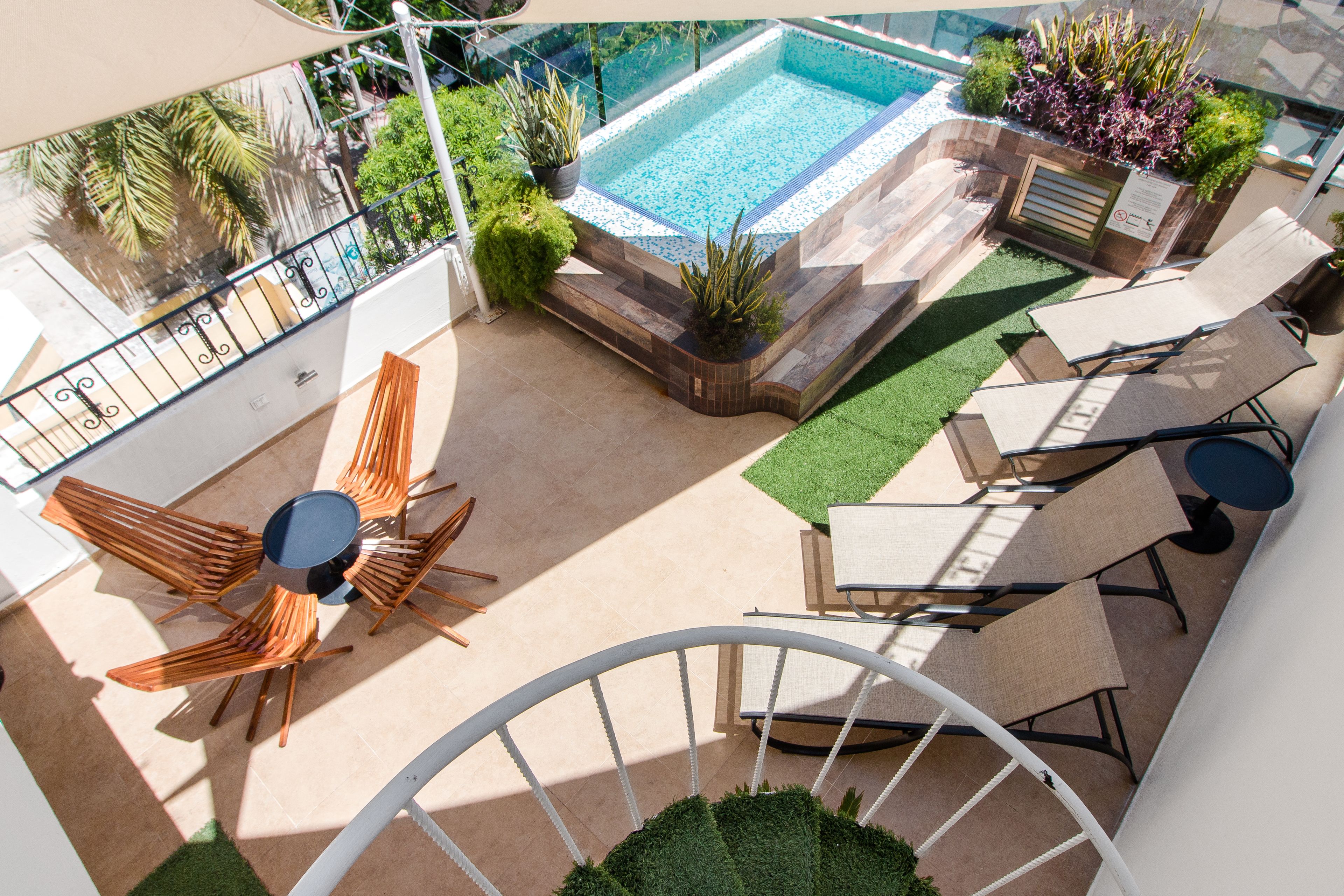 Un área de piscina en la azotea con piscina, sillas de descanso y una mesa de comedor.