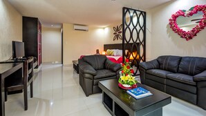 Ein modernes Wohnzimmer mit Sofa, Couchtisch und TV-Schrank. An der Wand befindet sich eine dekorative Blumenkomposition in Herzform.