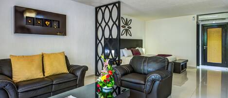 A modern living room with a black leather sofa, a glass coffee table, and a decorative wall piece.