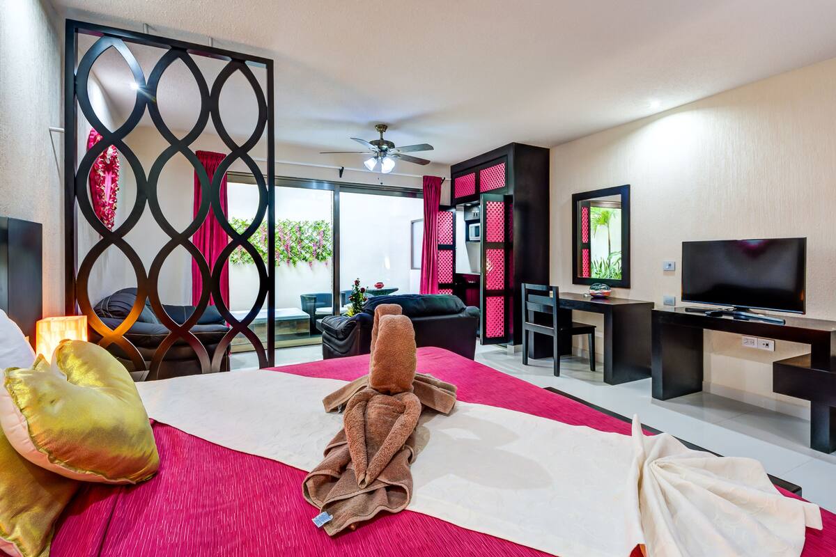 A hotel room with a bed, a desk, a television, and a view of the outdoors.
