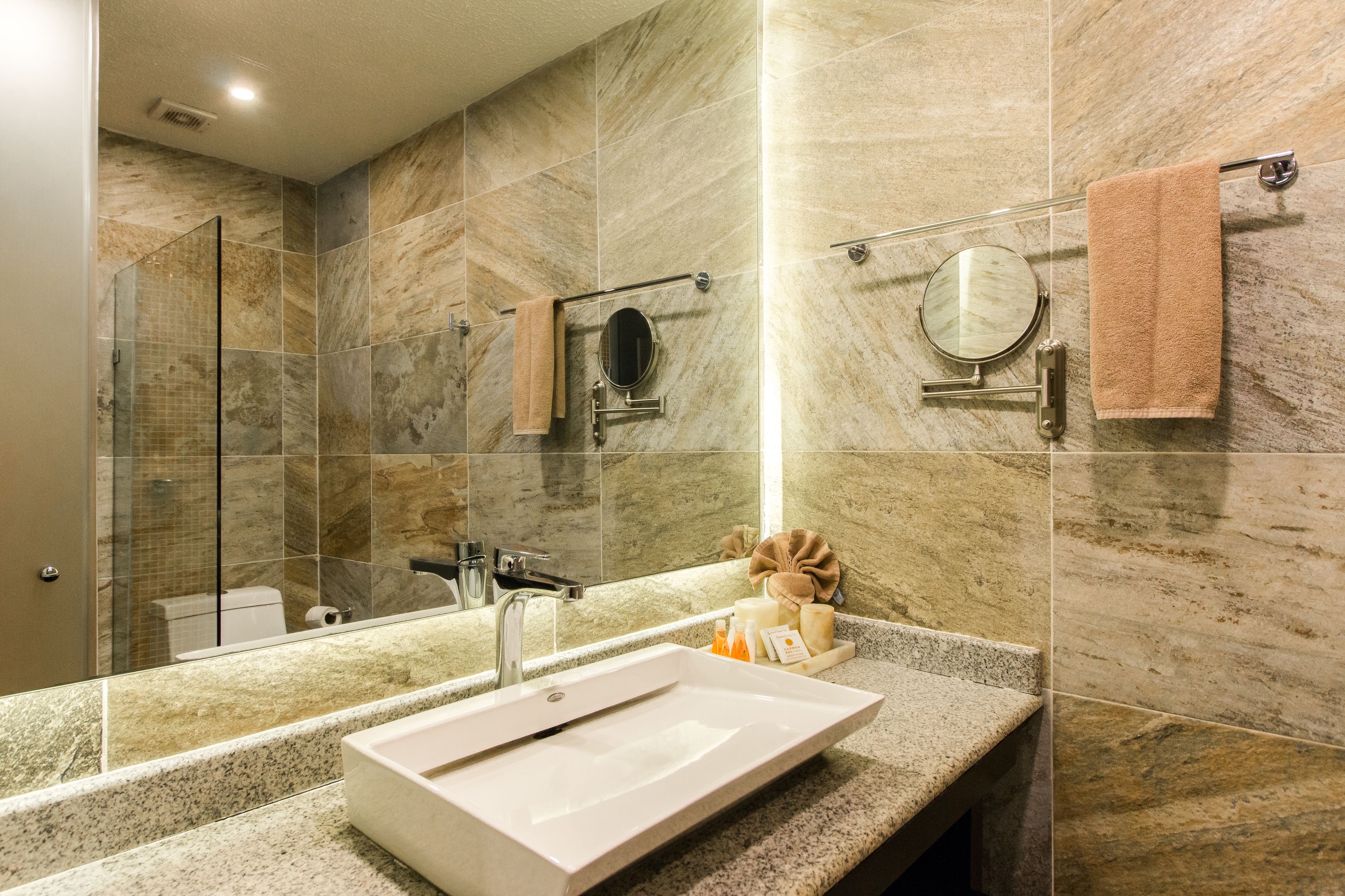 A modern bathroom with a large mirror, a sink, and a shower area.