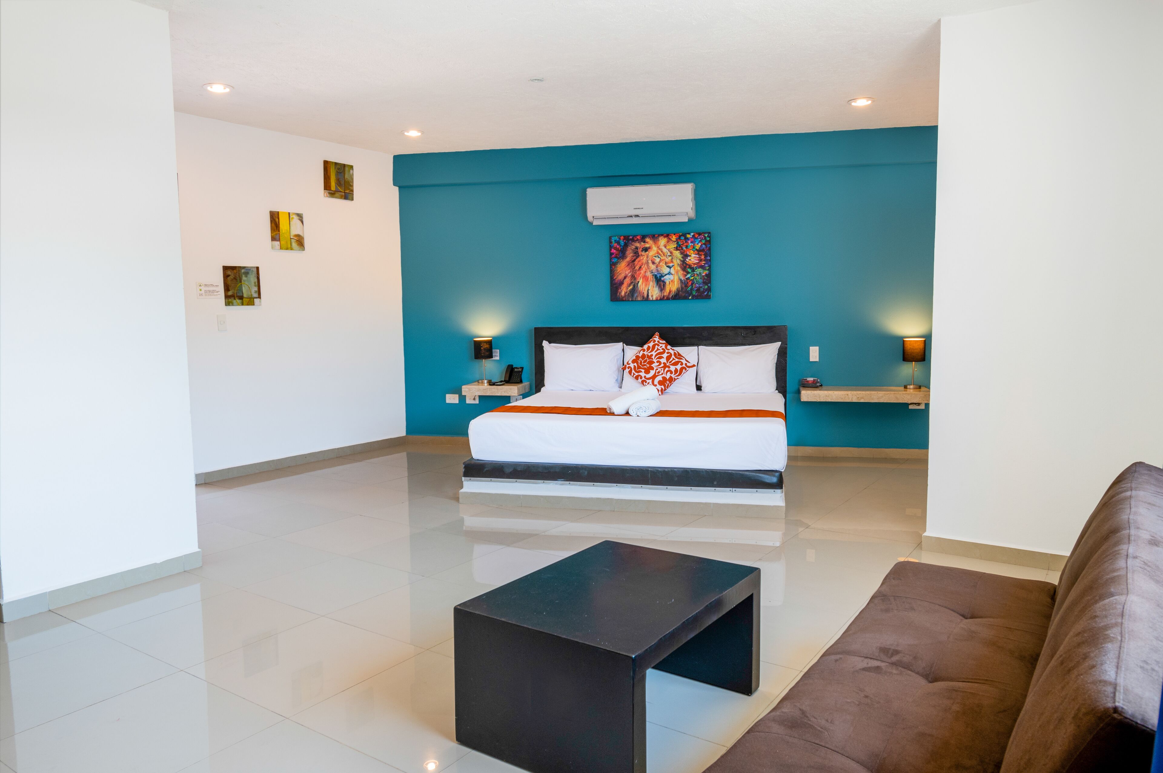 A modern hotel room with a large bed, a black coffee table, and a blue accent wall.