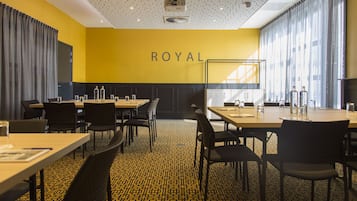 A conference room with a yellow wall, black chairs, and tables.