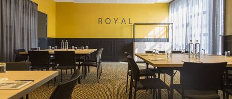 A conference room with a yellow wall, black chairs, and tables.