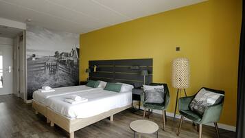 A hotel room with a bed, two bedside tables, a desk, a chair, and a lamp.