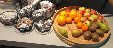 Una mesa de bufé con diversos alimentos, incluyendo frutas, quesos y productos envasados.