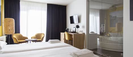 Habitación de hotel con dos camas, un escritorio, una silla y un televisor.