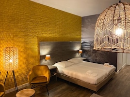 Ein Hotelzimmer mit einem großen Bett, einem Kopfteil, zwei Nachttischlampen, einem Wandbild und einer Pendelleuchte.