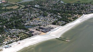 Vista aérea de un pueblo costero con zonas residenciales, una playa y un puerto deportivo.