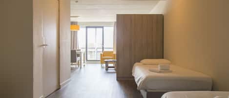 Habitación de hotel con dos camas, un escritorio, una silla y vistas al exterior.