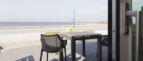 An outdoor seating area with a table and chairs, overlooking a beach.