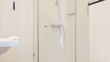 Een moderne badkamer met een douchecabine van glas, een wit toilet en een witte wastafel.