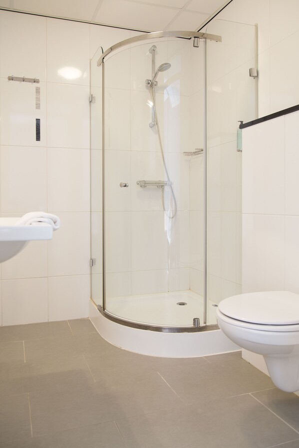 A modern bathroom with a glass-enclosed shower, a white toilet, and a white sink.