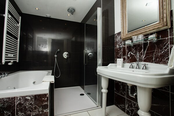 A modern bathroom with a glass-enclosed shower, a white bathtub, and a pedestal sink.