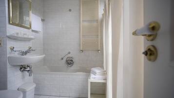Uma casa de banho com sanita, lavatório, banheira e chuveiro.