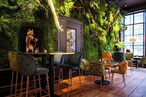 A restaurant with a green wall, wooden tables, and chairs.