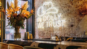 A bar area with a neon sign, a vase of flowers, and a brick wall.