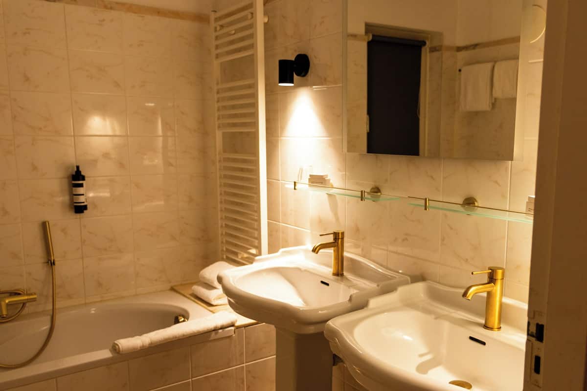 Un baño con dos lavamanos, una bañera y un perchero para toallas.