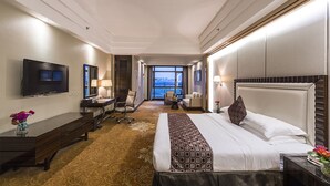 A hotel room with a large bed, a desk, a chair, a TV, and a view of the city. - Country Garden Phoenix Hotel Tongliao (Tongliao)