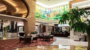 A spacious lobby with a high ceiling, a colorful abstract mural, a bar area, and a seating area with tables and chairs. - Country Garden Phoenix Hotel Tongliao (Tongliao)