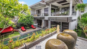 Una casa moderna de dos pisos con piscina, mobiliario exterior y un jardín cuidado.