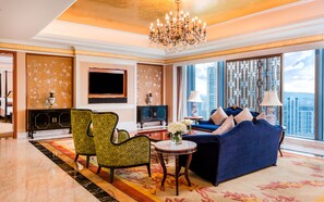 A spacious living room with a large chandelier, a blue sofa, patterned chairs, a TV, and a view of the city. - InterContinental Fuzhou by IHG (Fuzhou)