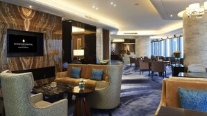 A hotel lobby with a marble wall, comfortable seating, a TV screen, and a dining area. - InterContinental Fuzhou by IHG (Fuzhou)