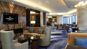A hotel lobby with a marble wall, comfortable seating, a TV screen, and a dining area. - InterContinental Fuzhou by IHG (Fuzhou)