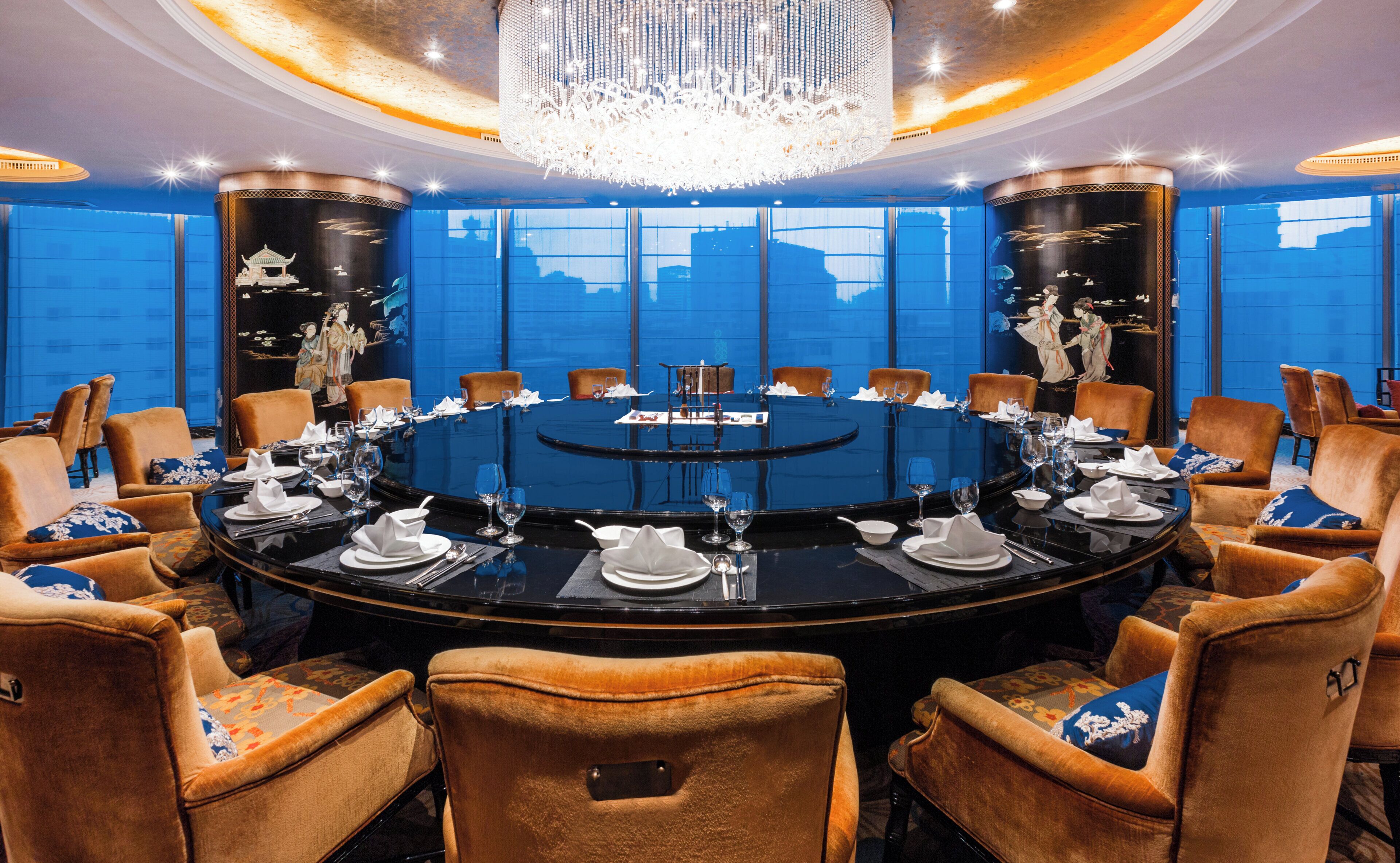 A round table with chairs, a chandelier, and artwork on the walls.