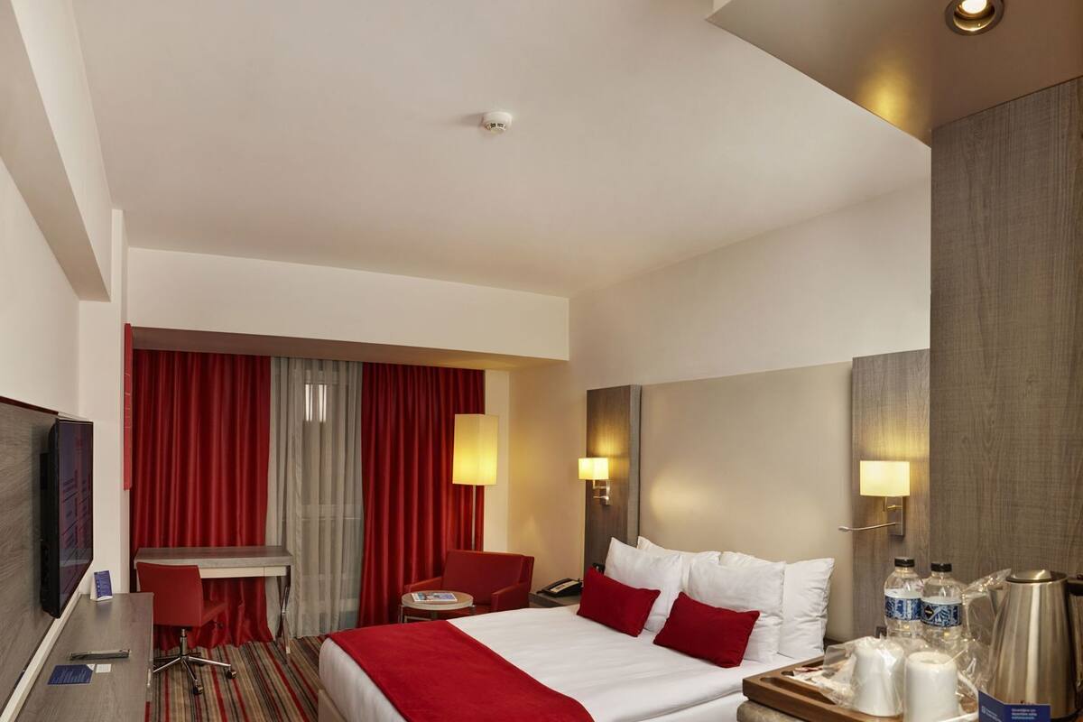 Een hotelkamer met een bed, bureau, stoel, televisie en koffiezetapparaat.