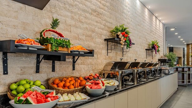 Un bufé con diversas frutas y verduras, como sandía, manzanas y naranjas.