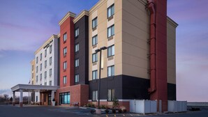 A multi-story hotel with a modern design, featuring a covered entrance and a parking lot.