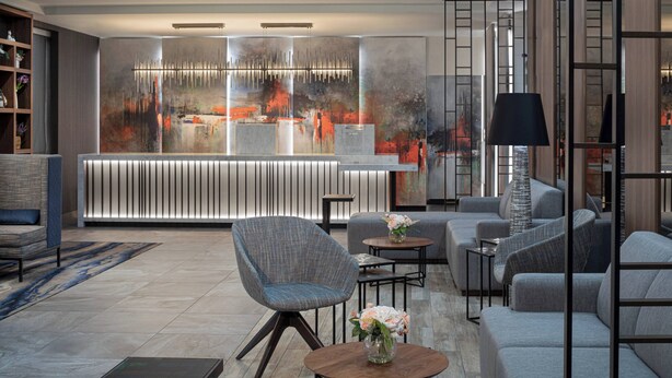 A modern lobby with a reception desk, seating area, and a large abstract painting on the wall.