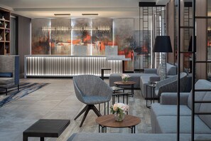 Eine moderne Lobby mit einer Rezeption, einer Sitzecke und einem großen abstrakten Gemälde an der Wand.