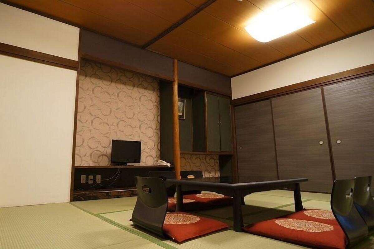 Ett traditionellt japanskt rum med tatamimattor på golvet, ett lågt bord och en tv.