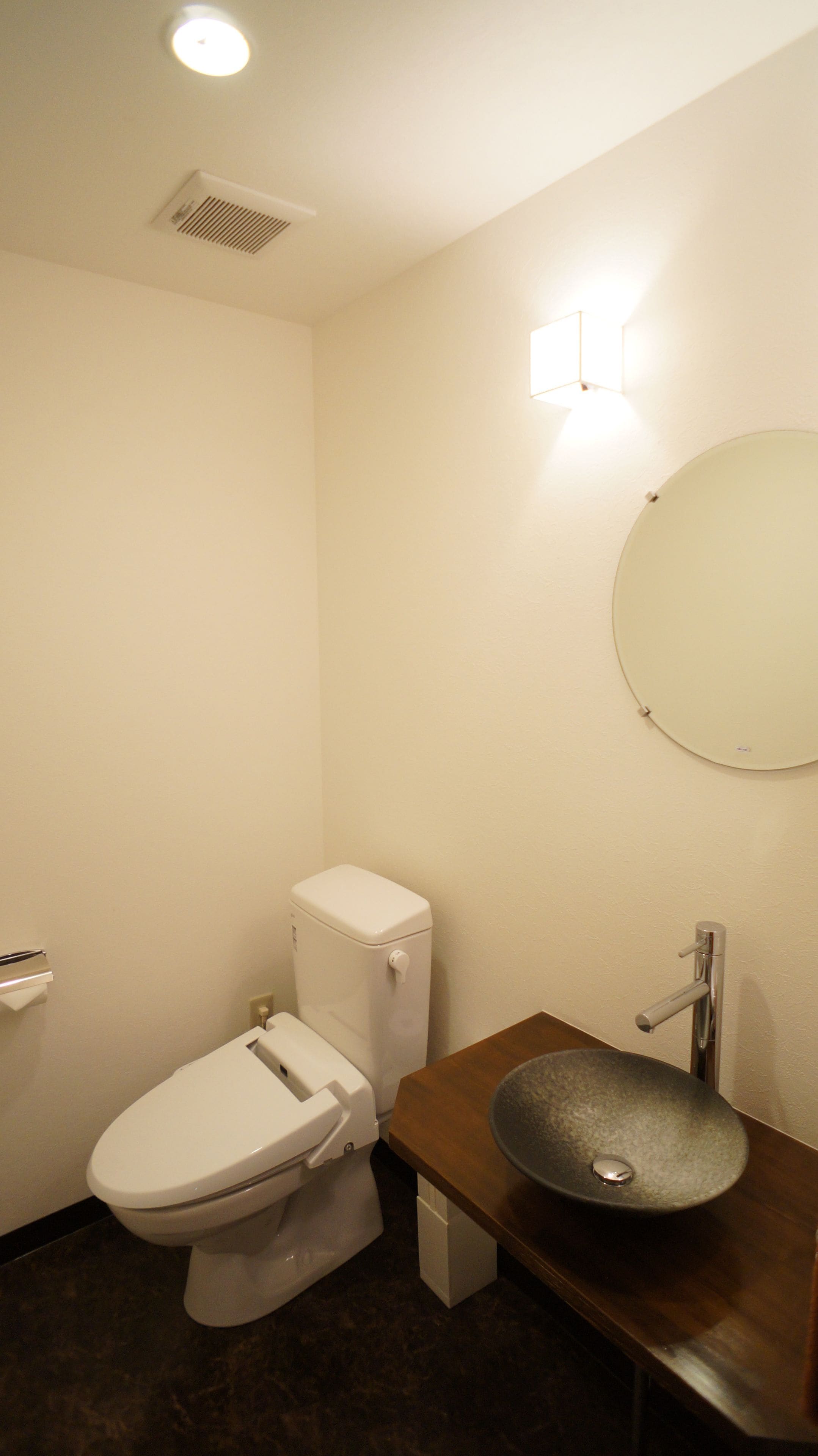A small, clean bathroom with a toilet, sink, and mirror.