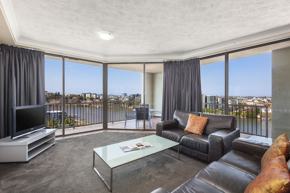 A modern living room with a flat-screen TV, leather sofa, and a glass coffee table.
