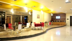 A conference room with glass walls, a stage with a podium, and tables with chairs. - Jolin Hotel (Makassar)